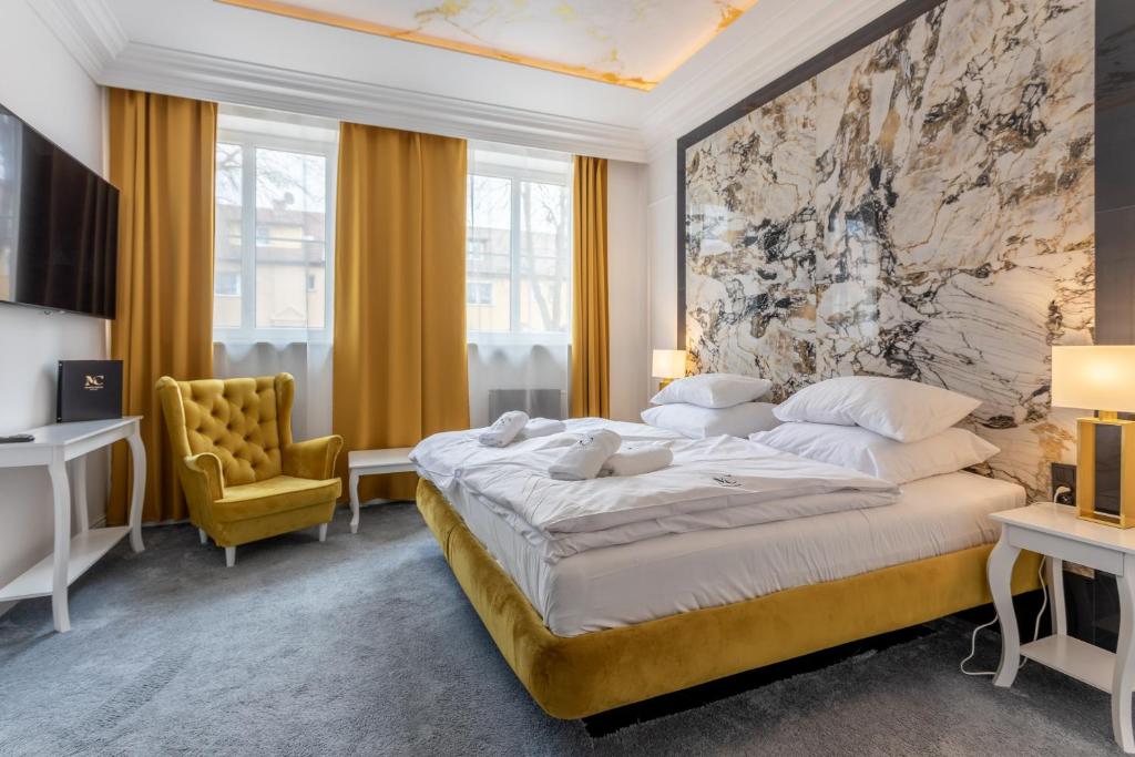 斯维诺乌伊希切Monte Carlo Boutique Hotel的一间卧室配有一张大床和一张黄色椅子