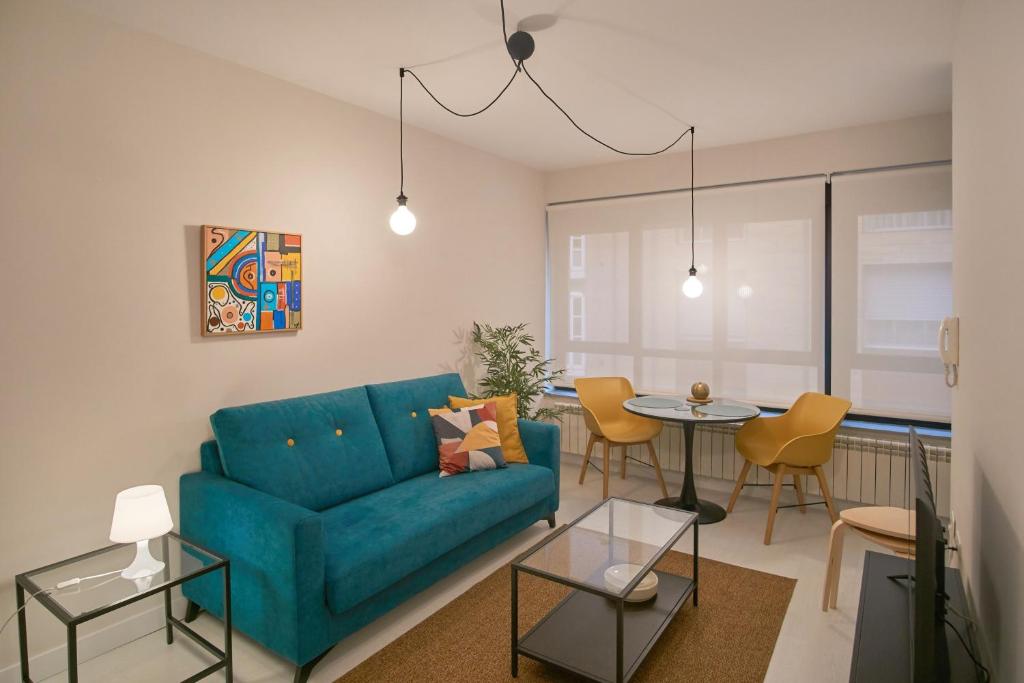 蓬费拉达Apartamentos Los Arroyos的客厅配有蓝色的沙发和桌子