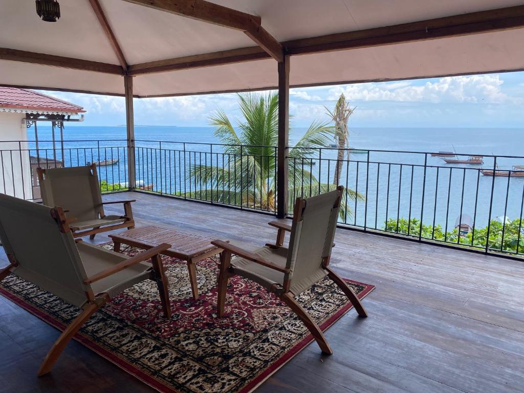 桑给巴尔David Livingstone's Home的阳台配有两把椅子和一张桌子,享有海景。