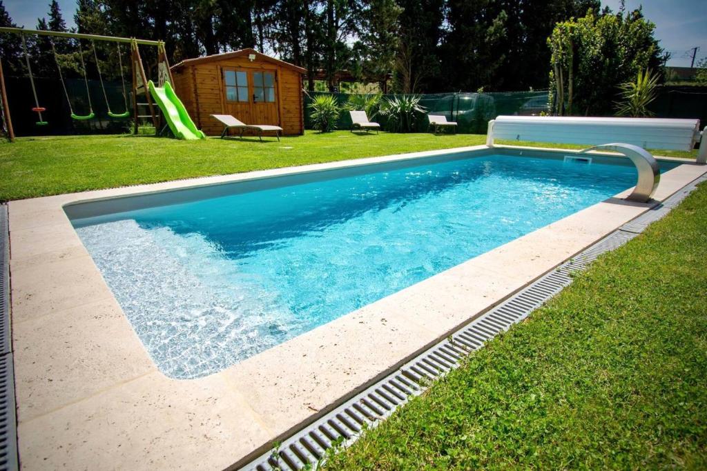 阿维尼翁Appartement d'une chambre avec piscine partagee jacuzzi et jardin clos a Avignon的一个带滑梯的庭院内的游泳池