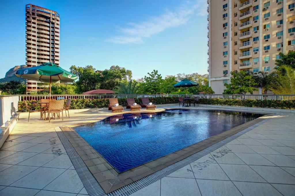 里约热内卢里约热内卢巴拉达蒂茹卡品质酒店 的一座大楼内的游泳池,配有椅子和遮阳伞