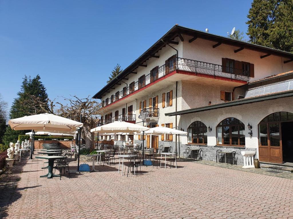 阿尔梅诺Hotel Madonna di Luciago的前面有桌子和伞的建筑