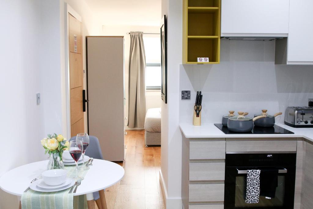 伦敦Deluxe and Modern Studio Apartment in Sydenham的白色的厨房配有桌子和台面