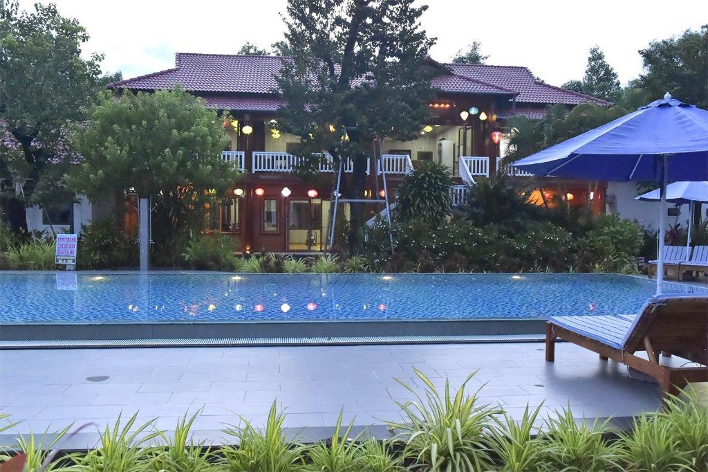 富国Rain Forest Resort Phu Quoc的一个带长凳和遮阳伞的游泳池