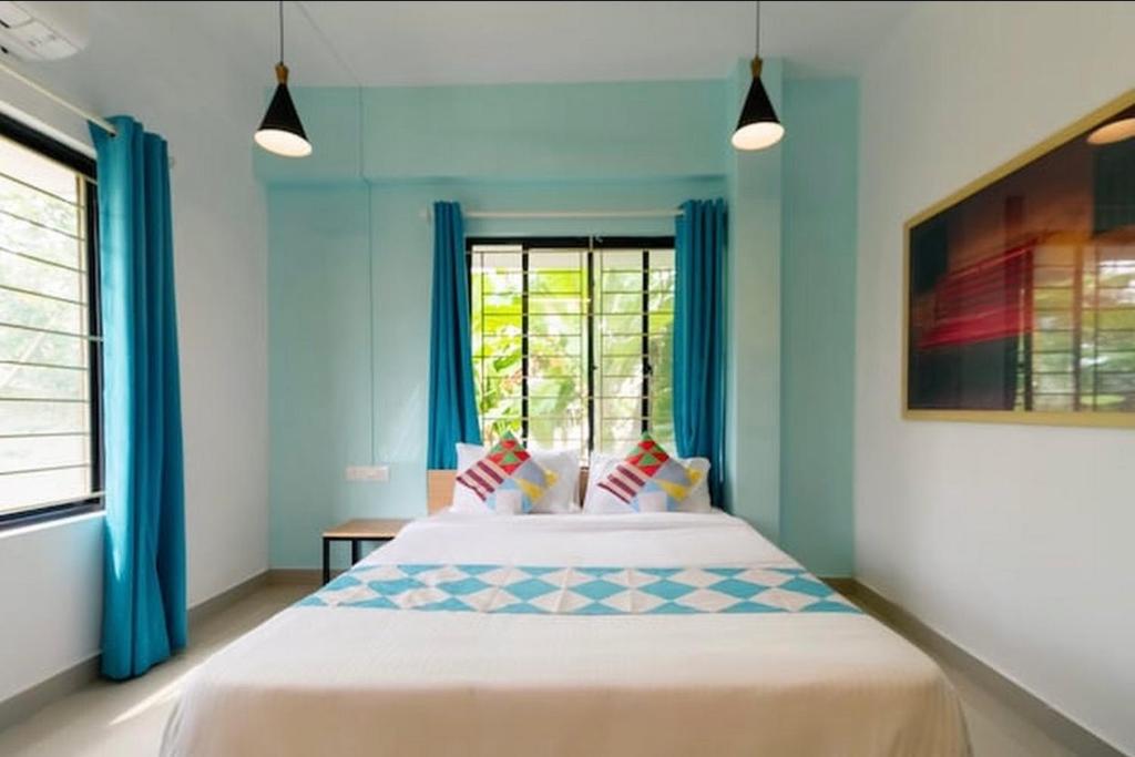 科泽科德Ecoville suites的一间卧室配有一张带蓝色窗帘的床和一扇窗户