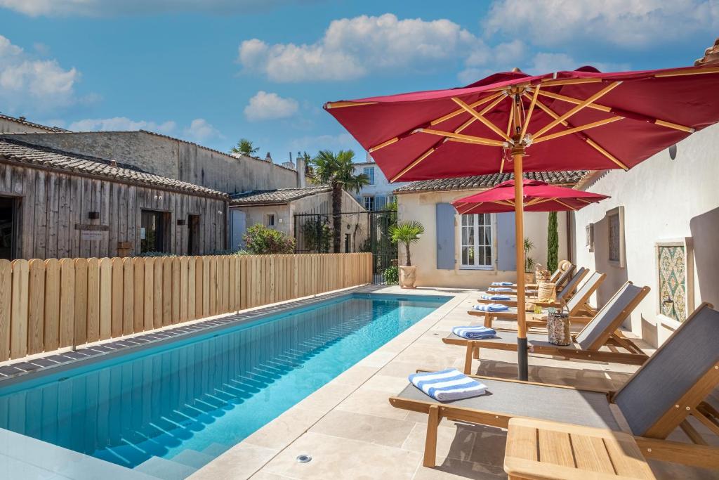圣马丹德雷La Baronnie Hôtel & Spa - Teritoria的房屋旁的游泳池配有遮阳伞和椅子