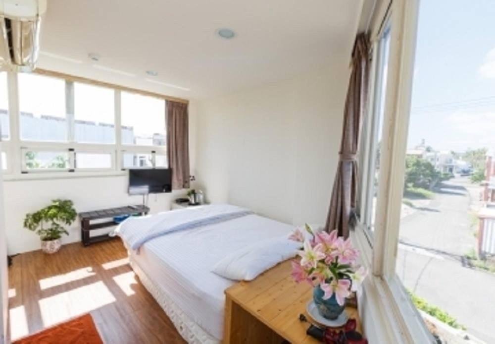 恒春古城垦丁峰晴海湾馆的一间卧室设有一张床和一个大窗户