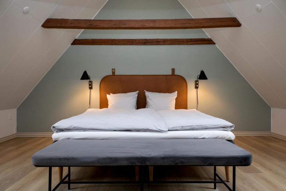 洛肯Hotel Løkken Strand的阁楼上的一张带白色床单和枕头的床