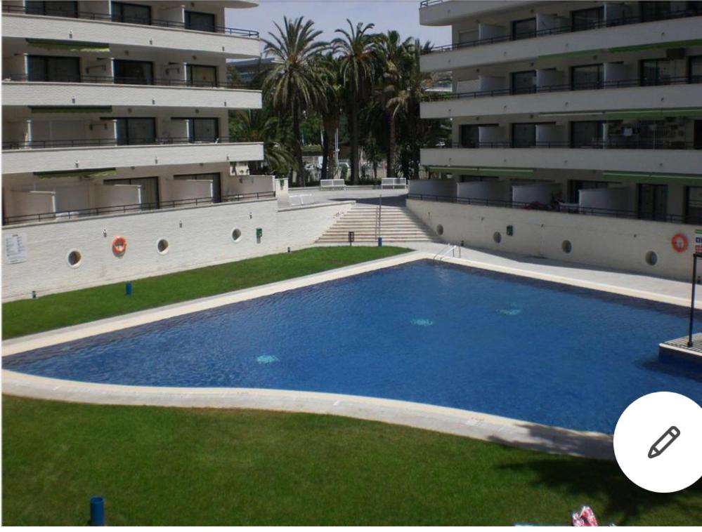 萨洛APARTAMENTO CERCA DEL PASEO Y PORT AVENTURA的大楼前的大型蓝色游泳池
