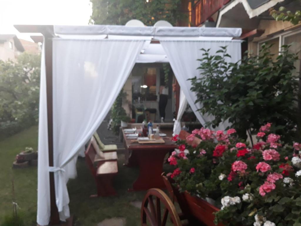 阿赫洛伊къща за гости Градина的白色的凉亭,配有桌子和鲜花