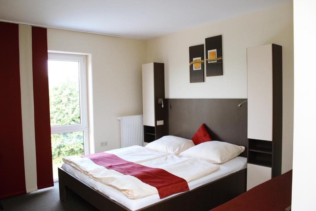 亨施泰特-乌尔茨堡阿瑞娜酒店的一间卧室配有一张床铺,床上铺有红色毯子