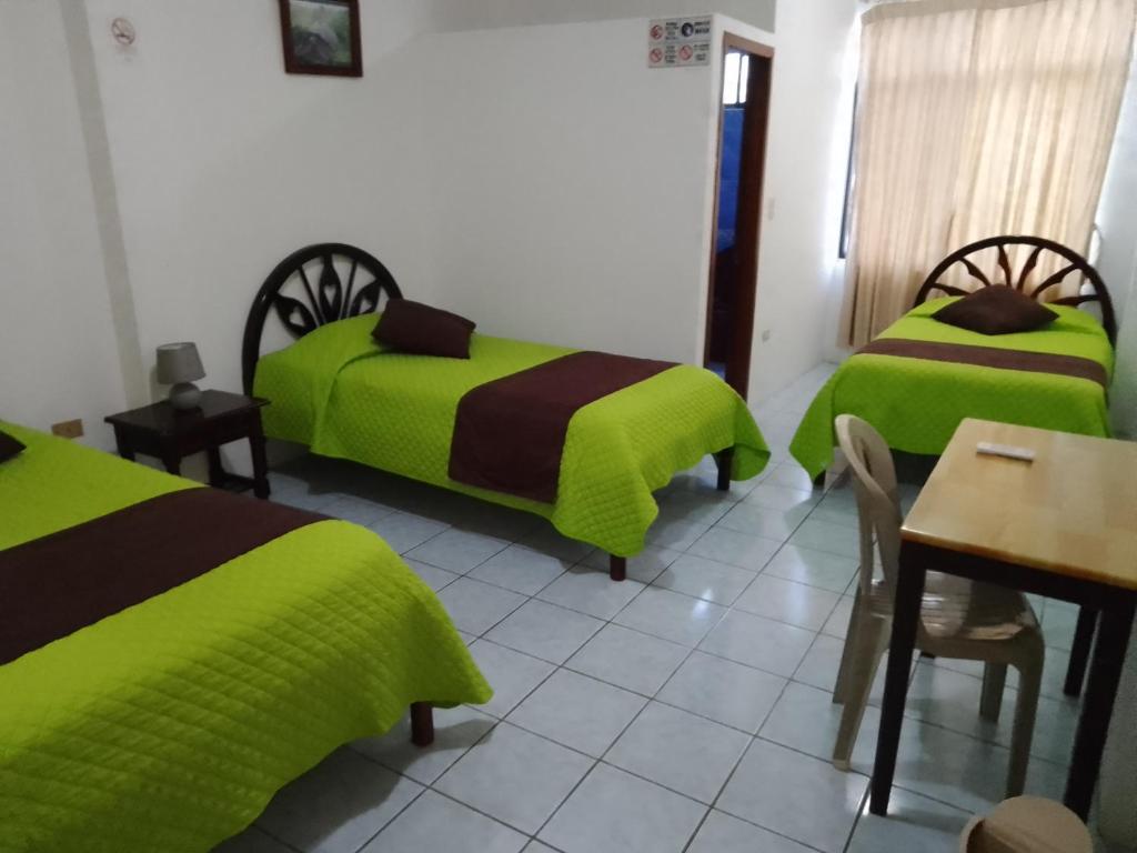 比亚米尔港Hotel Isla del descanso的客房设有两张床、一张桌子和一张桌子以及椅子。