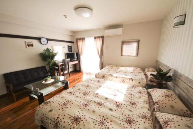 那霸Chura Gahna House Tsubogawa Naha的一间带两张床的卧室和一间客厅