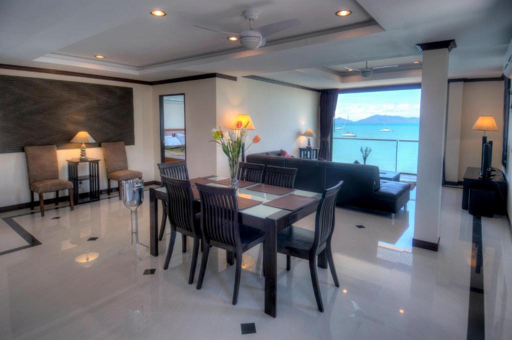 苏梅岛Emerald Beach-Front Apartments Fishermans Village的用餐室以及带桌椅的起居室。