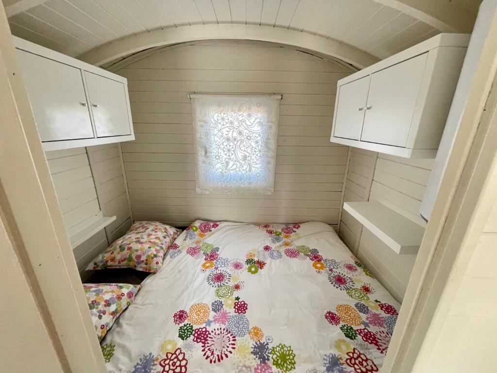 滨海贝亨Pipowagen aan zee的一个小房间的一个床位,设有窗户