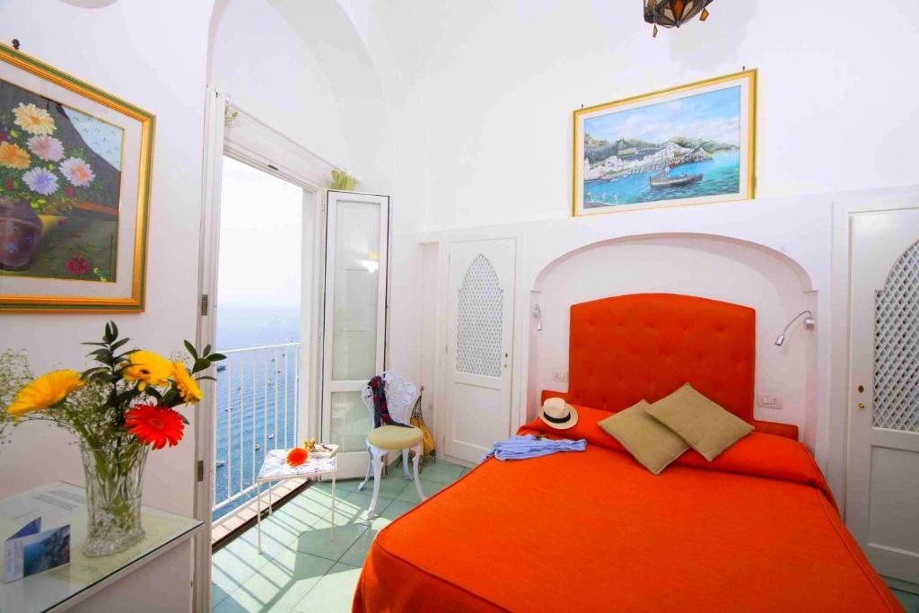 阿马尔菲拉宁法酒店的一间带红色床的卧室和一个阳台