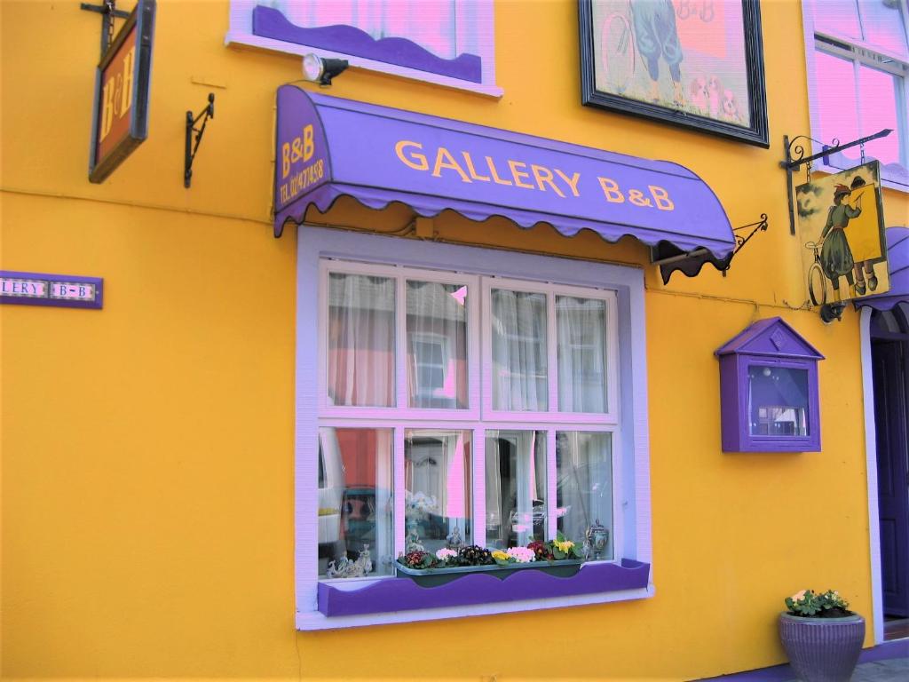 金塞尔The Gallery B&B, the Glen, Kinsale ,County Cork的黄色的建筑,有窗户和标志