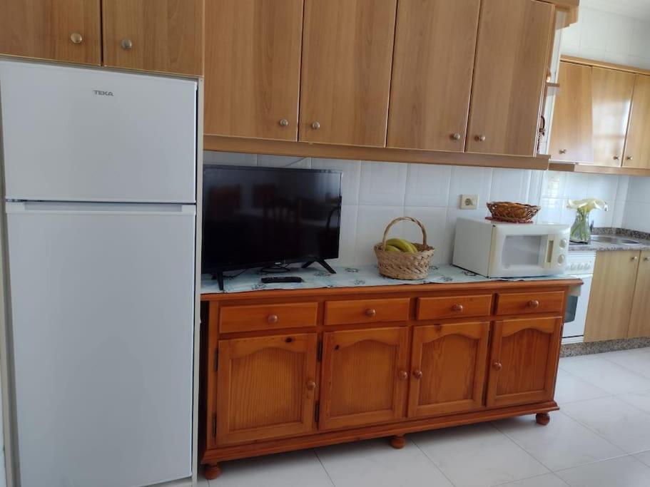 格罗韦Apartamento en San Vicente de O Grove的厨房配有白色冰箱和微波炉