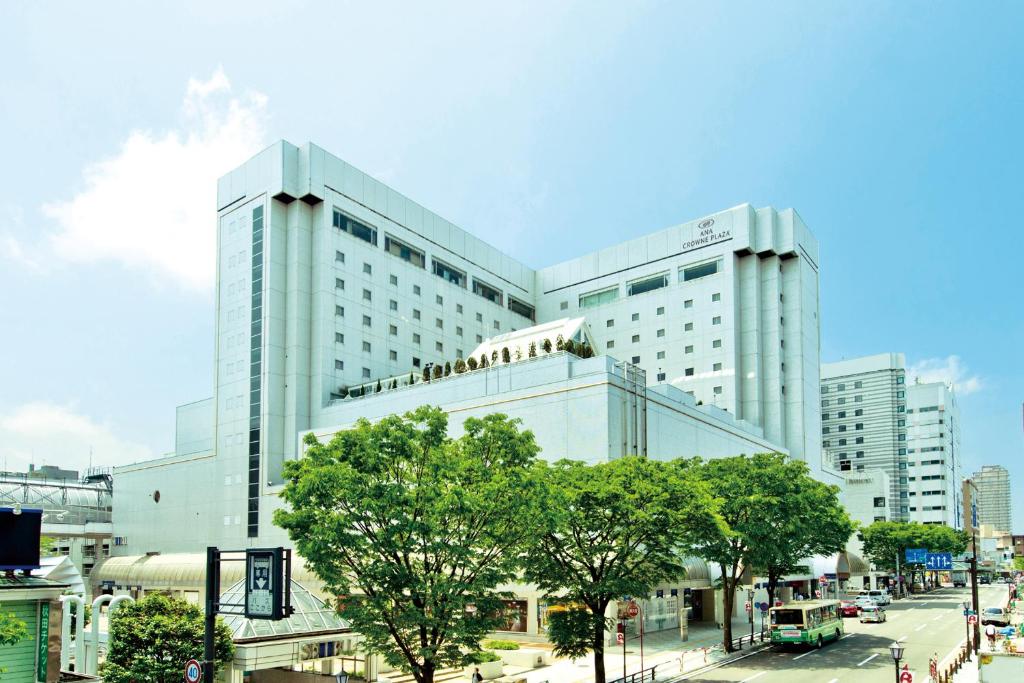 秋田ANA Crowne Plaza Akita, an IHG Hotel的前面有树木的白色大建筑