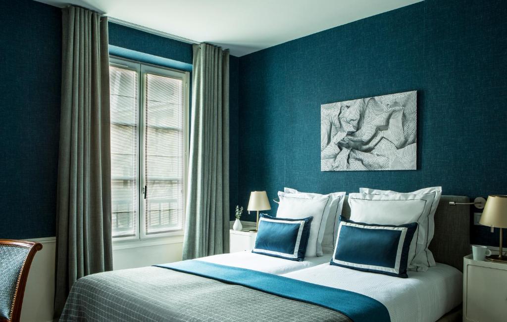 巴黎卢浮宫广场法兰西精神酒店的一间卧室配有一张蓝色墙壁的床和一扇窗户