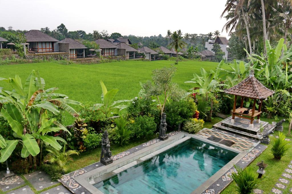 乌布Mira Family Cottages的花园内的游泳池,带凉亭