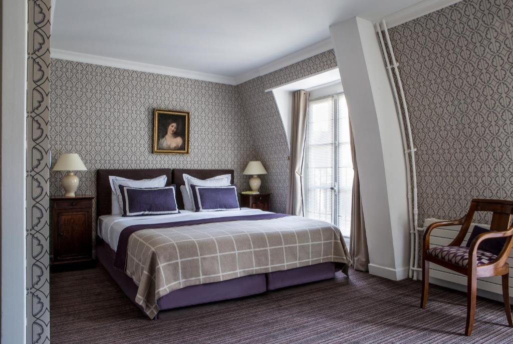 巴黎Hôtel d'Orsay - Esprit de France的一间卧室配有一张带蓝色枕头的床和一扇窗户。