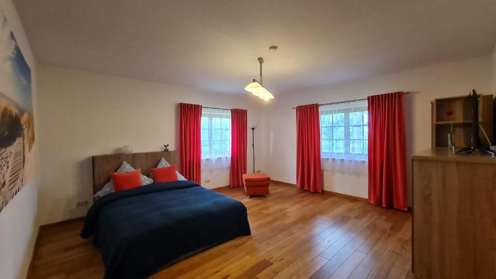 GustowIdylle im Grünen的一间卧室配有红色窗帘和一张床,铺有木地板