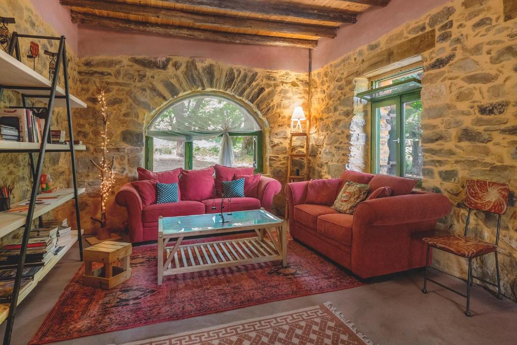 SémbronasHani Kastania - Chania retreat for families and groups for holidays and workshops的客厅设有两张红色的沙发和石墙