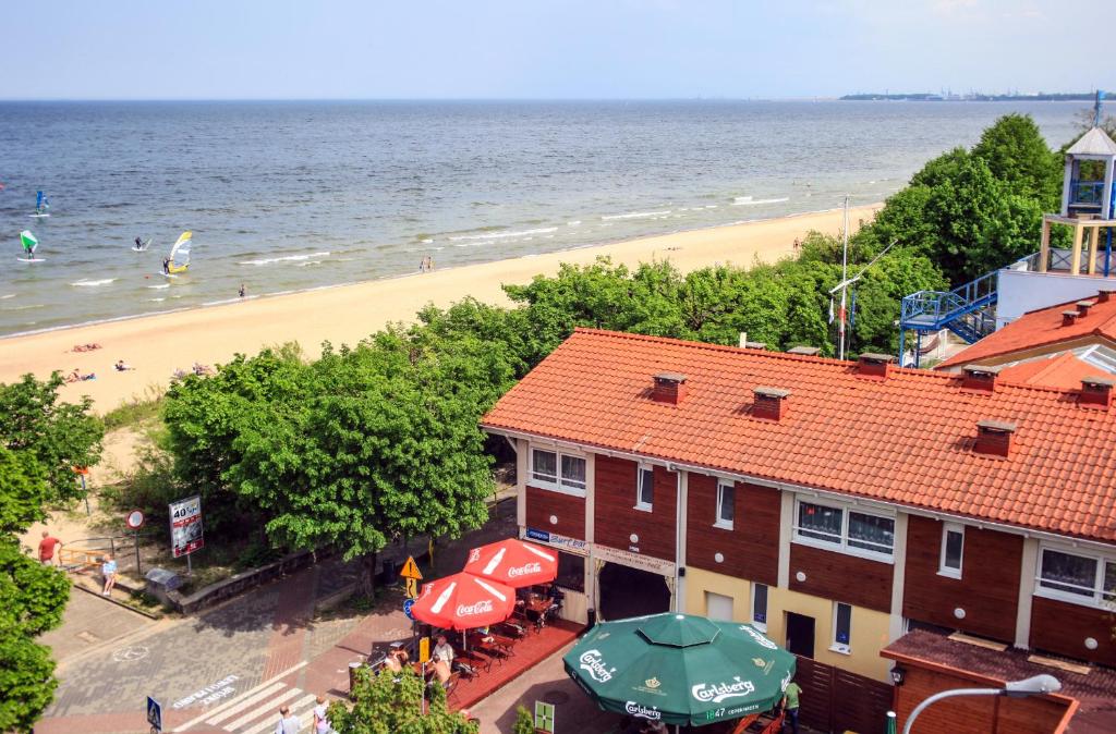 索波特索波特游艇俱乐部旅馆的享有海滩和一座带遮阳伞的建筑的景致。