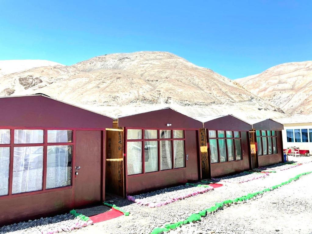 斯潘格米克Pangong Delight Camps and Cottages的一座红色的建筑,背景是一座山