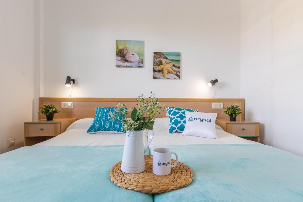 萨洛里维埃拉阿里萨尔公寓酒店的一张带两个杯子的床和一个鲜花托盘