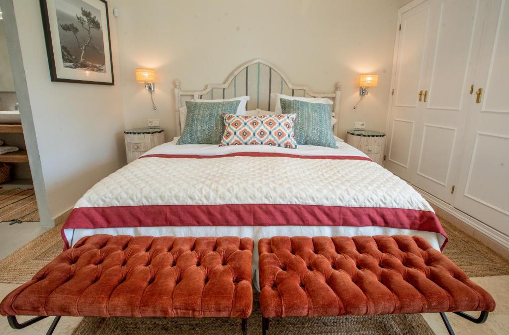 马贝拉Apartamento en Guadalmina con vistas al Golf的一间卧室配有一张大床和红色的搁脚凳