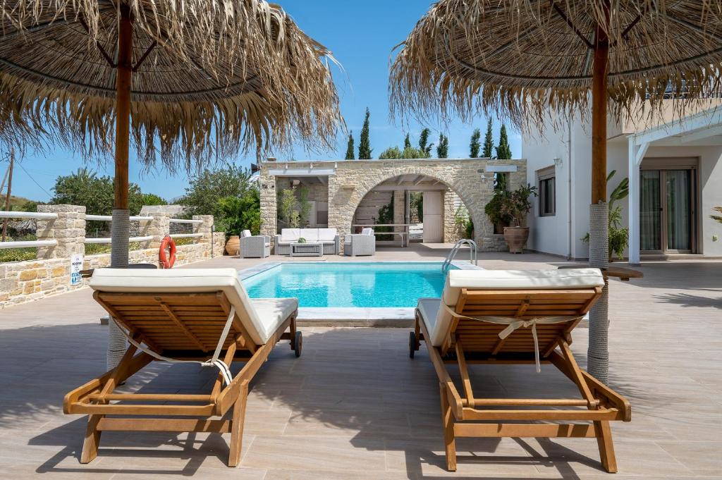 卡米拉日Golden Sky Villa的别墅 - 带带2把椅子和遮阳伞的游泳池