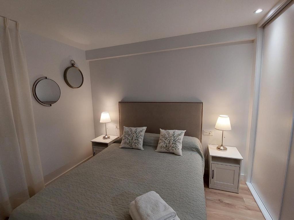 莱昂Ordoño II Suites con Aire Acondicionado y Wifi的一间卧室配有一张带两张桌子和两盏灯的床。