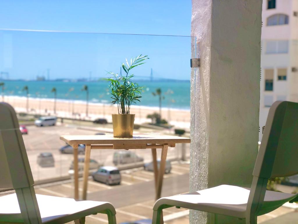 圣玛丽亚港Valdelagrana vistas al mar, piscinas primera linea cadiz的海滩阳台顶部的桌子上放着盆栽植物