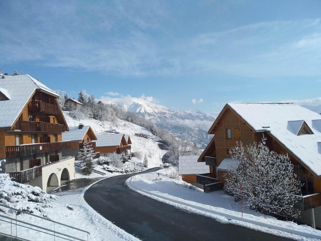 普华露Location Pra-Loup Vacances à 1500的村里有积雪覆盖的道路,有建筑
