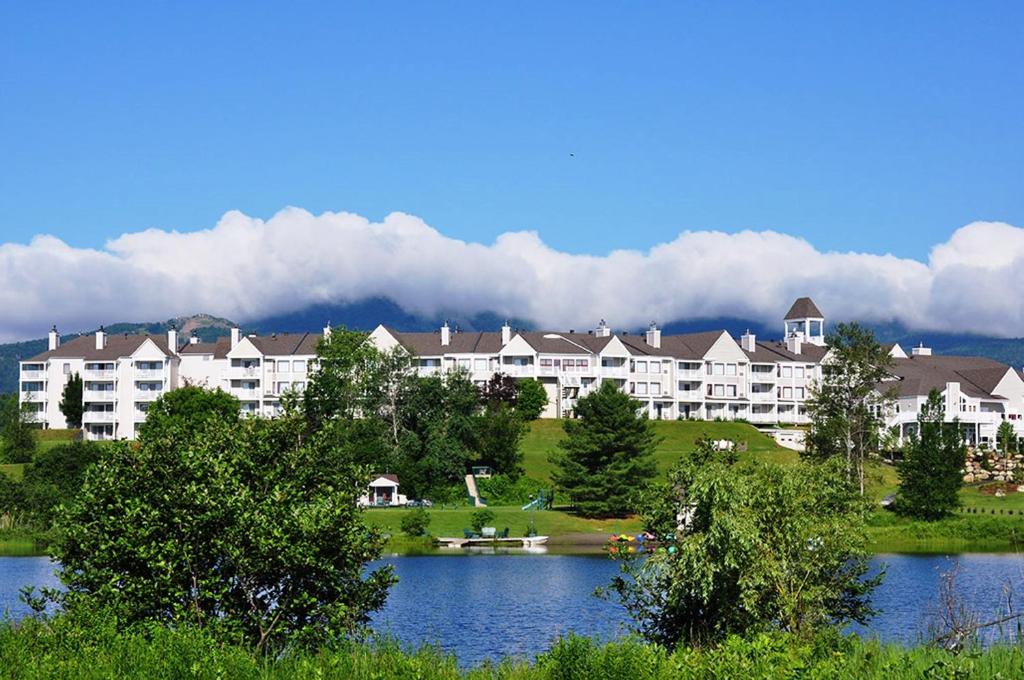 梅戈格德斯萨布勒斯高尔夫庄园酒店的一座大型公寓楼,前面有湖泊