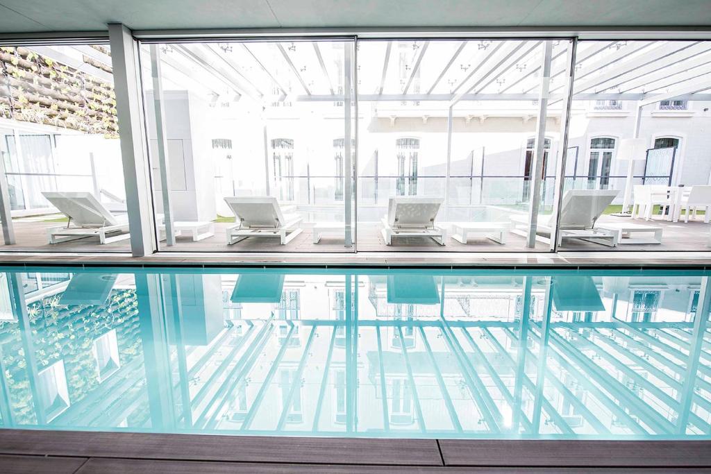 里斯本贝萨酒店－力比达德的一座带椅子和桌子的建筑中的游泳池