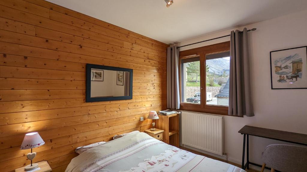 德沃吕伊La Souloise的卧室设有木墙、一张床和窗户