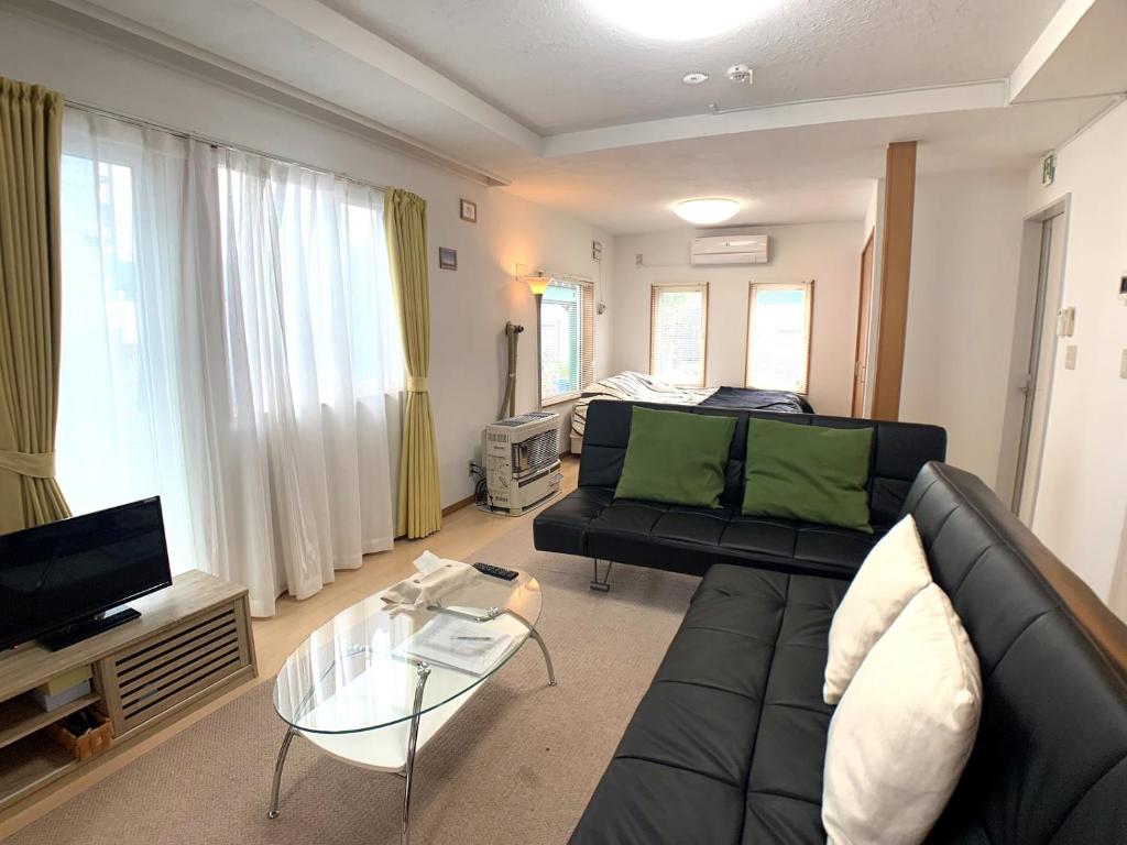 旭川Nagayama Home的客厅配有黑色沙发和电视