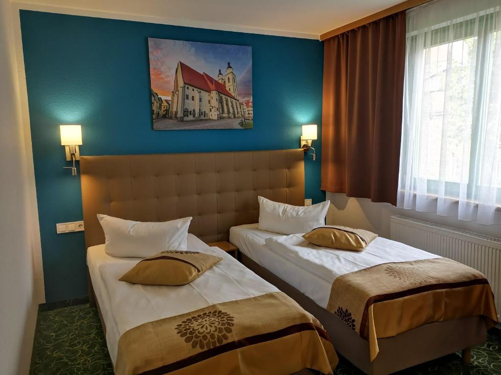 路德斯塔德·威特比威滕伯格ACRON酒店的两张位于酒店客房的床,拥有蓝色的墙壁