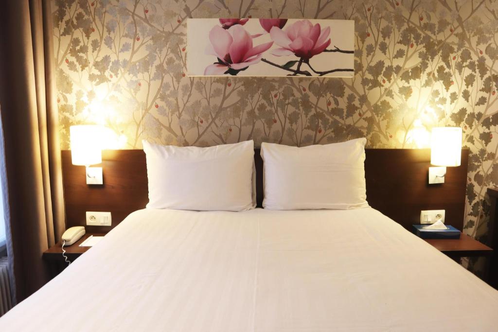 巴黎蒙帕纳斯提姆敖德萨酒店的一间卧室配有一张带两盏灯的大型白色床。