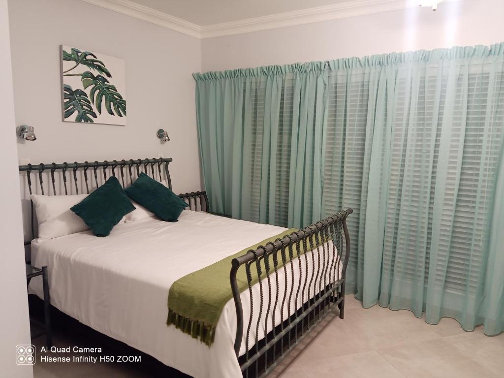 博克斯堡4 on Verbena的一间卧室配有床和绿色窗帘