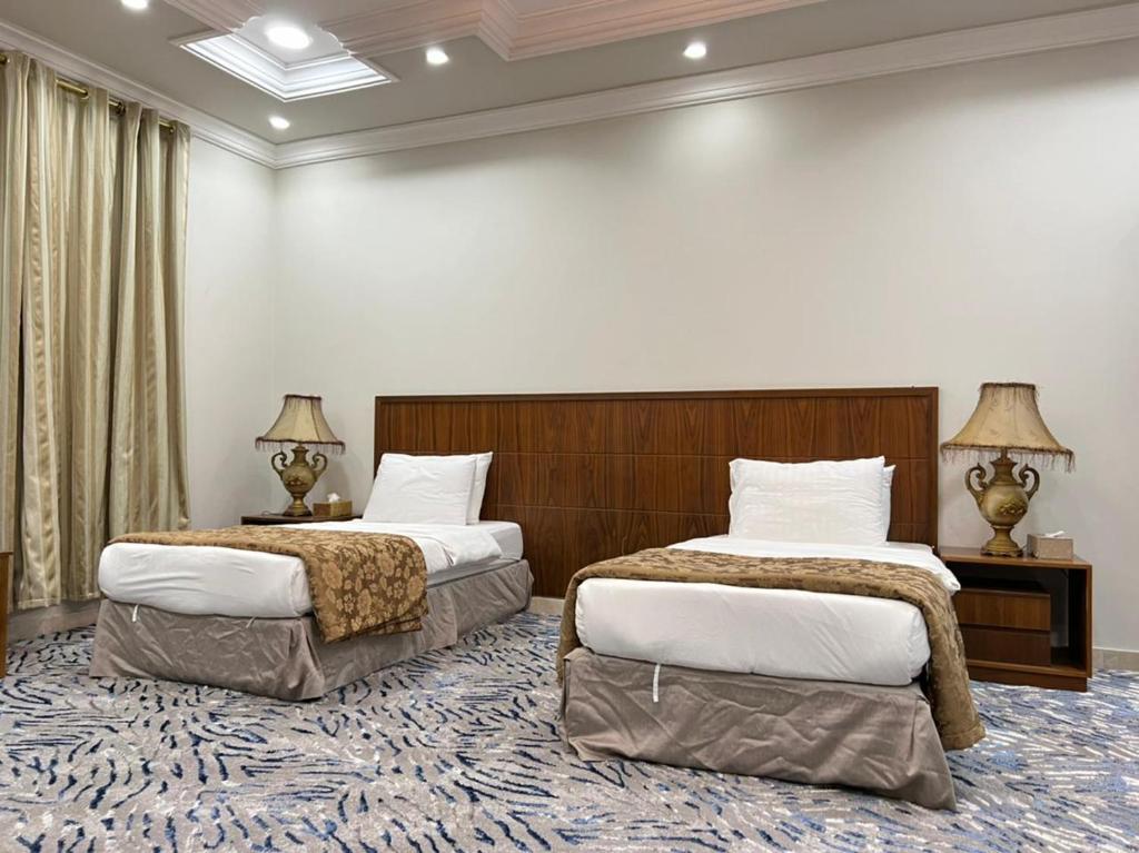 欧拉سويت ان العلا للشقق المفروشة الخاصة Sweet In alula Apartments and organizing tours的酒店客房设有两张床和两盏灯。