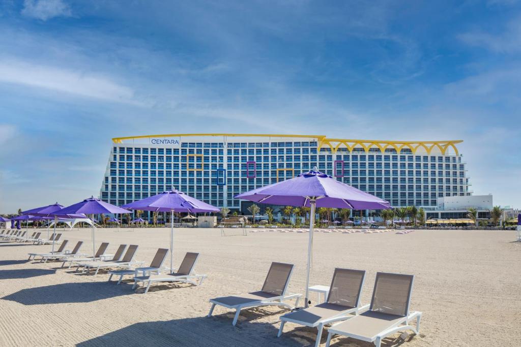 迪拜Centara Mirage Beach Resort Dubai的海滩上的一排椅子和遮阳伞