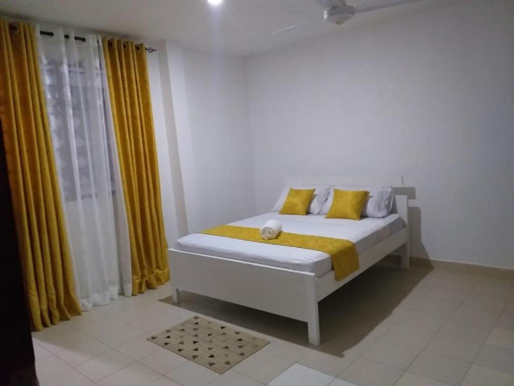 姆特瓦帕Hyven's Apartments的白色卧室配有黄色窗帘的床