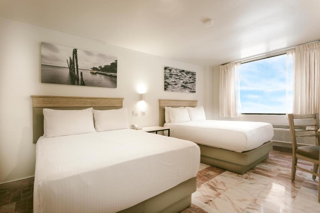 比亚埃尔莫萨Gamma Villahermosa Centro的酒店客房设有两张床和窗户。