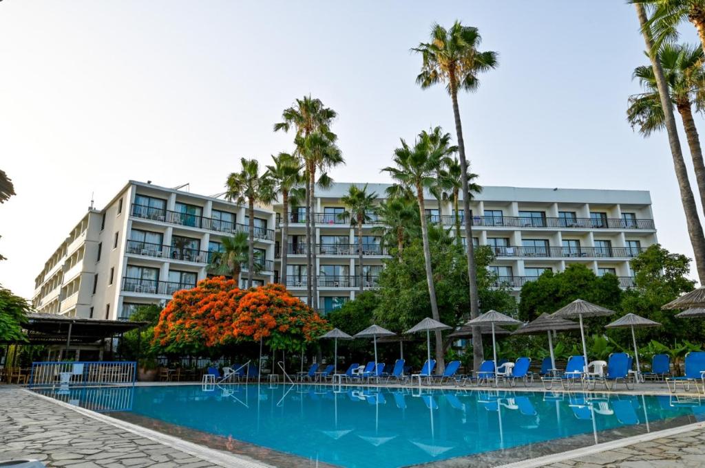 帕福斯维罗尼卡酒店的一座拥有游泳池、棕榈树和遮阳伞的酒店