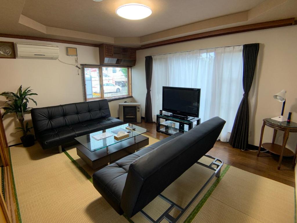 旭川TY-Home的客厅配有黑色真皮沙发和电视