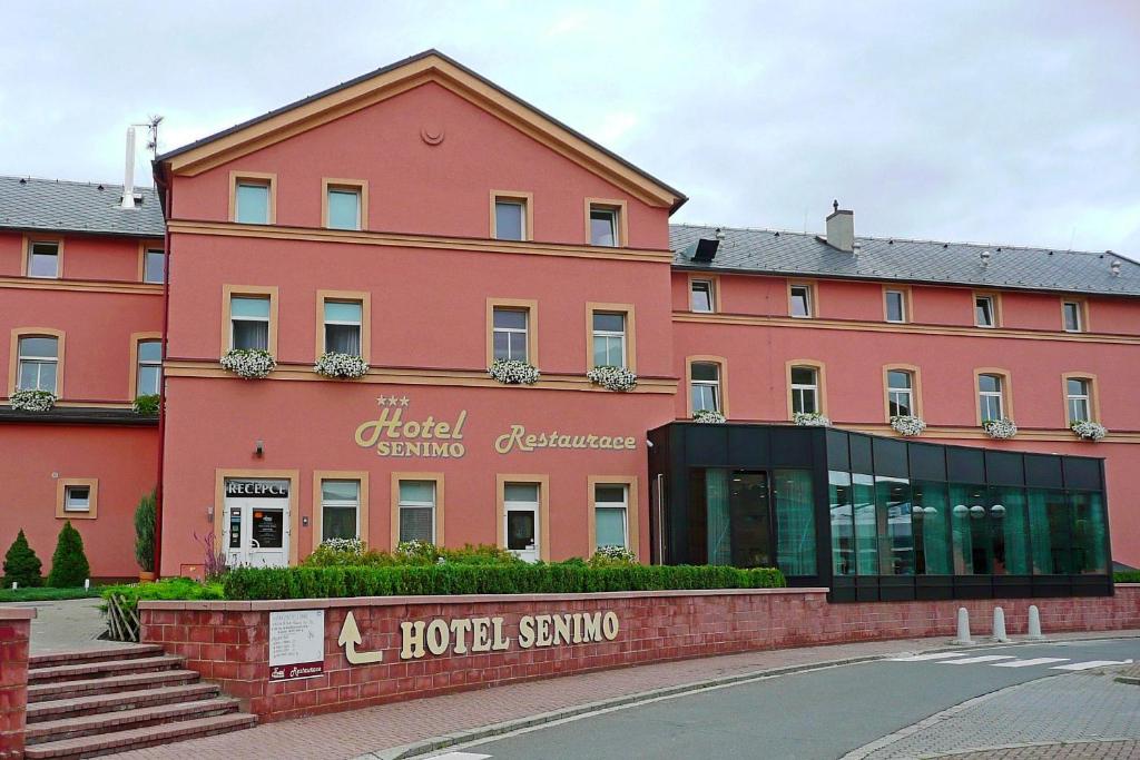 奥洛穆茨瑟尼莫酒店的一座粉红色的大建筑,前面有一家酒店
